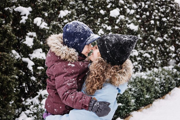 Portrait of happy family mother and son in snowy winter park outdoors portrait of mom and kid boy