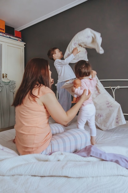 편안한 아침에 침대 위에서 노는 행복한 가족의 초상화. 주말 가족 여가 시간 개념입니다.
