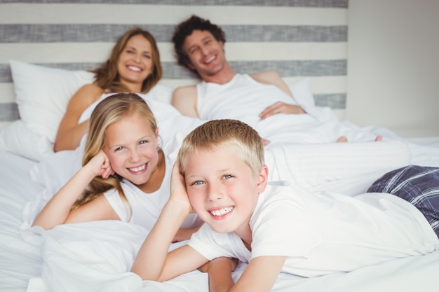 Portrait of happy family resting on bed