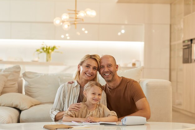 portrait of happy family smiling while helping cute little girl drawing on studying at home