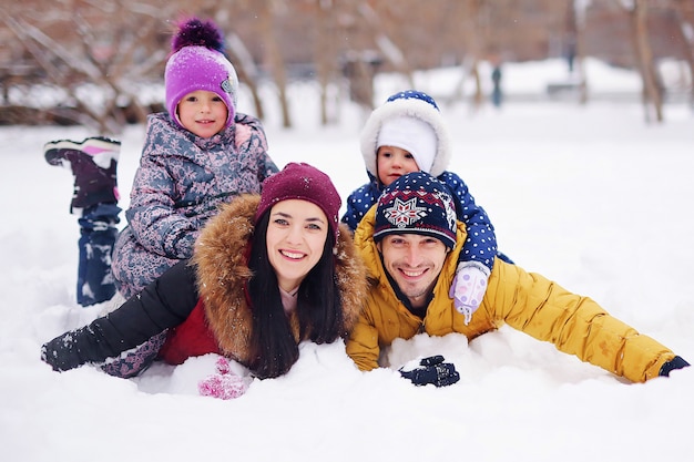 Portrait of happy family in the winter. Smiling parents with their children. Handsome father and beautiful mother with little cute daughters having fun in the show park. Pretty kids, nice woman