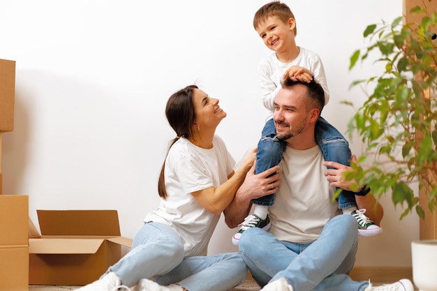 Portrait of happy family with cardboard boxes in new house at moving day