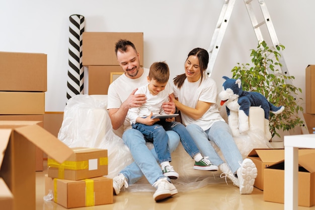 Portrait of happy family with cardboard boxes in new house at moving day