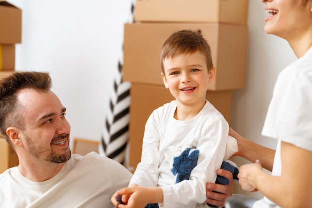 Portrait of happy family with cardboard boxes in new house at moving day