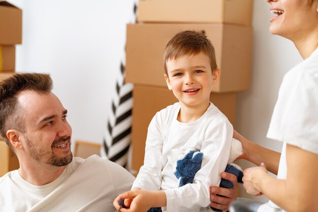 Photo portrait of happy family with cardboard boxes in new house at moving day