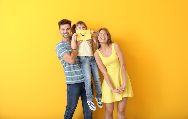 Ritratto di famiglia felice con sorriso disegnato sul foglio di carta contro il colore