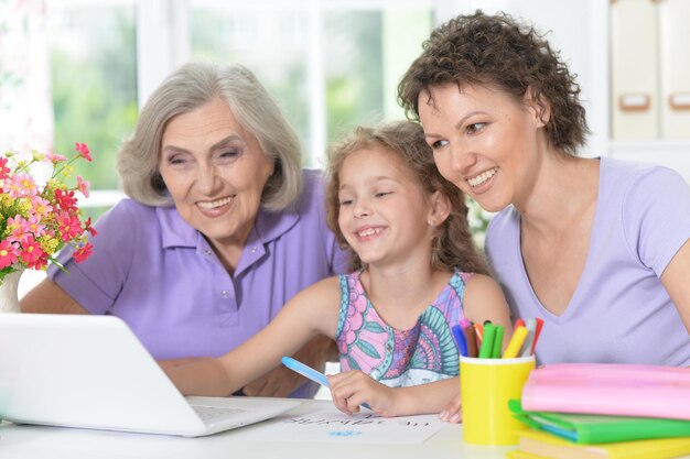 Ritratto della famiglia felice con il computer portatile a casa