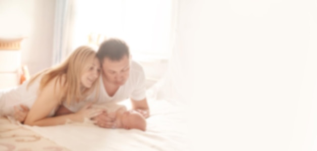 Portrait of a happy family with a newborn baby. Background for text with people in blur