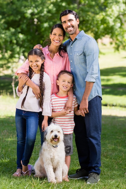 Portrait of happy family with their pet dog standing in park