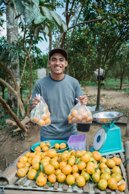 Portrait of happy farmer selling orange fruit