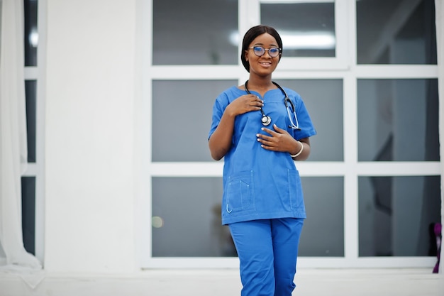 Portrait of happy female african american young doctor pediatrician in blue uniform coat and stethoscope against window in hospital Healthcare medical medicine specialist  concept