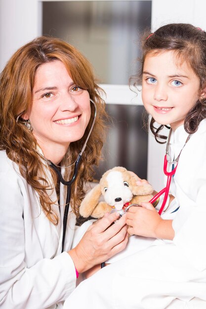 Photo portrait of happy female doctor and girl holding teddy bear in hospital ward