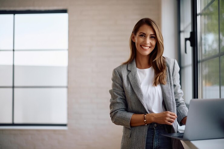 Photo portrait of happy female entrepreneur working on laptop and looking at camera