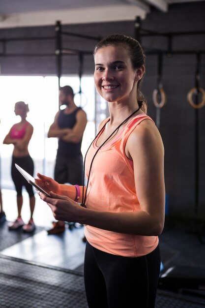 Photo portrait of happy female fitness instructor holding clipboard in gym