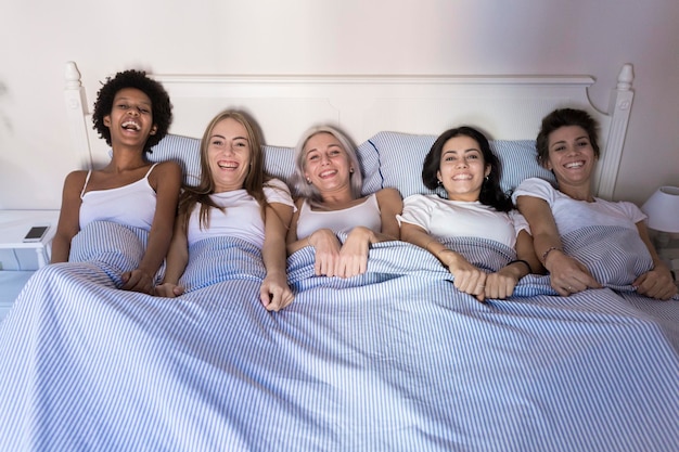 침대에 나란히 누워 있는 행복한 여자 친구들의 초상화
