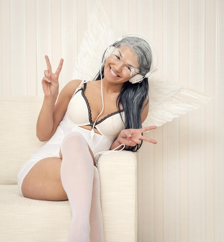 Photo portrait of happy female model in angel costume gesturing peace sign on sofa