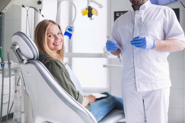 Portrait of happy female patient near dentist in clinic