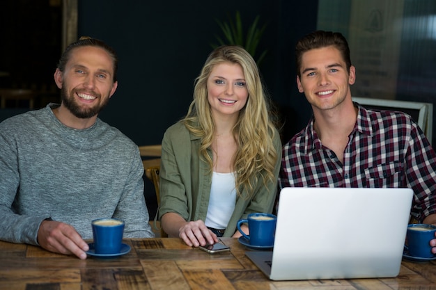 Portrait of happy friends having coffee at table in cafeteria