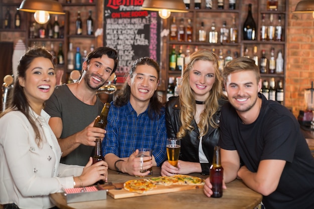 Portrait of happy friends having pizza with beer