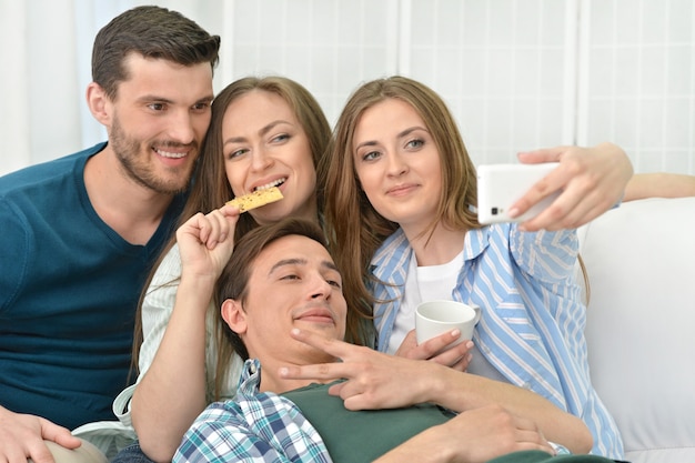 Portrait of happy friends making selfie at home