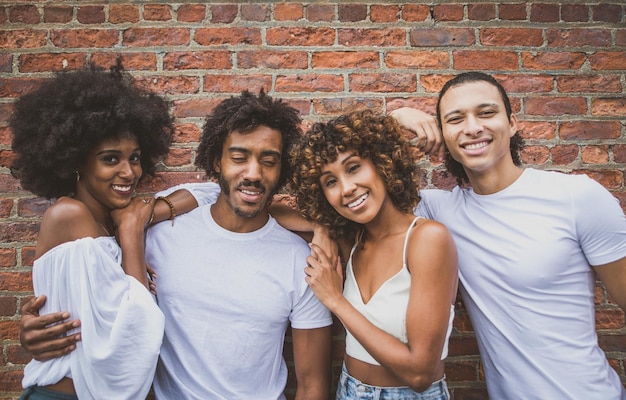 Portrait of happy friends standing against brick wall