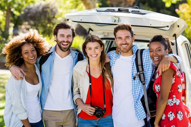 Portrait of happy friends standing with arm around in park