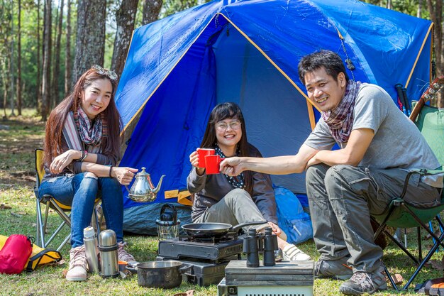 Photo portrait of happy friends with tea camping in forest
