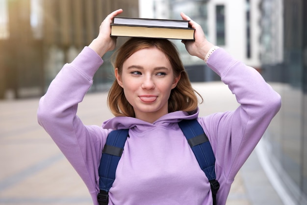 幸せな面白い十代のティーンエイジャーの女の子の若い女性の大学や大学の大学生の本の肖像画