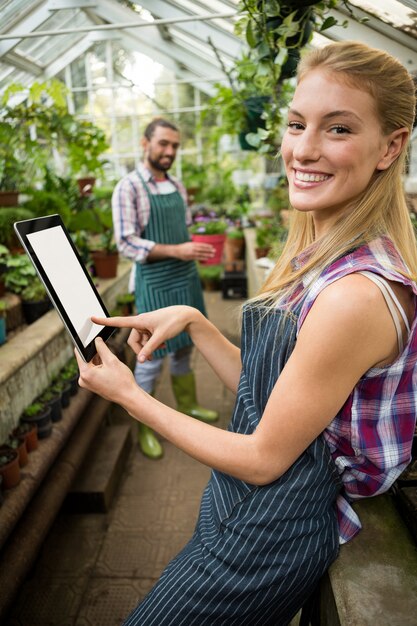 温室でデジタルタブレットを使用して幸せな庭師の肖像画