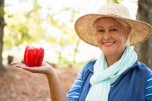 Portrait of happy gardener with red bell peppers at garden