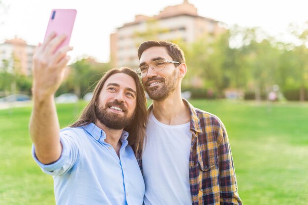 Ritratto di una coppia gay felice che si fa un selfie nel parco in una giornata di sole