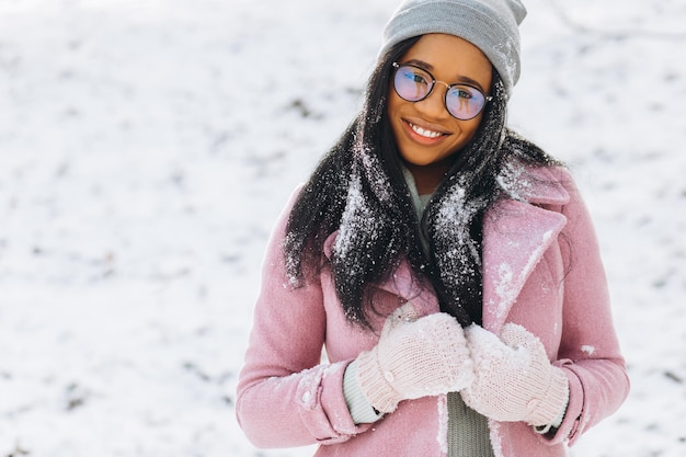 Portrait of happy girl African American young woman in glasses and gloves is smiling at winter