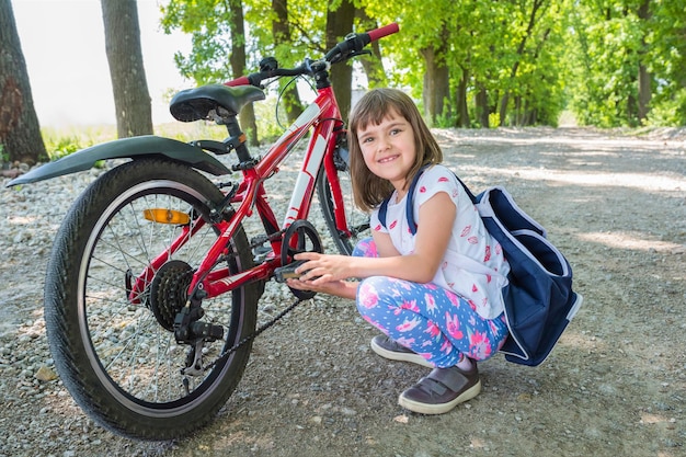 A portrait of a happy girl and bike in the park Closeup