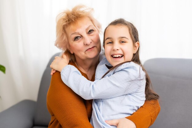 Portrait of happy girl and her grandmother looking at camera at home.