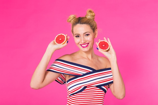 Photo portrait of happy girl holding halves of orange near face