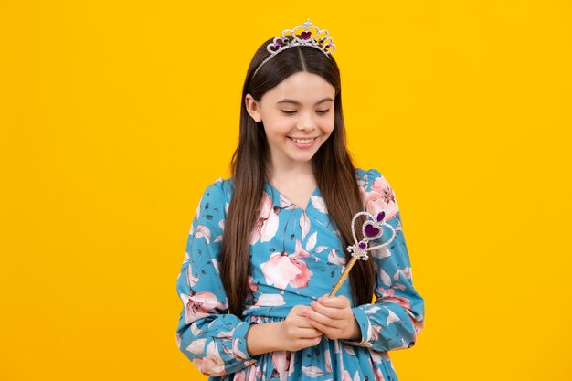 Portrait of happy girl princess in tiara holding magic wand teenager queen with golden crown