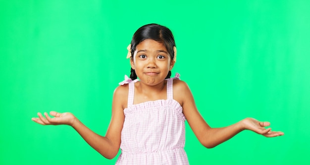 Portrait happy and a girl shrugging on a green screen background in studio to gesture doubt or whatever Smile question and confused with an adorable little female child on chromakey mockup