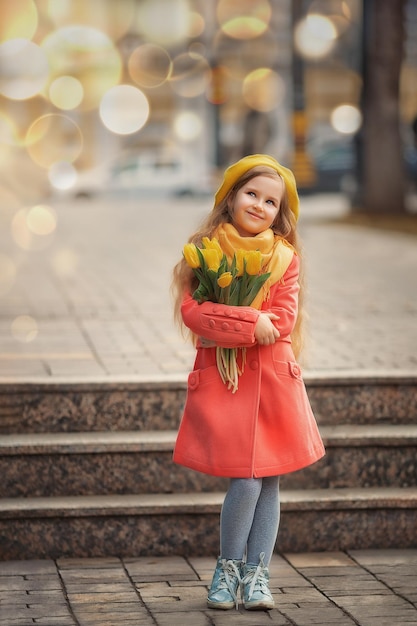 国際女性の日のための花春の散歩に黄色いチューリップの花束を持つ幸せな女の子の肖像画