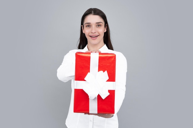 Portrait of a happy girl with gift box isolated over gray background Woman holding gift present