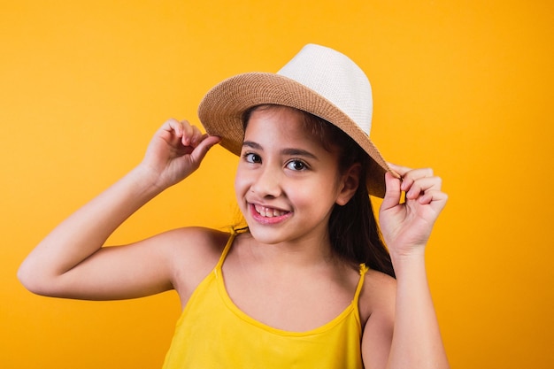 Portrait of happy girl with hat and yellow dress on yellow background.