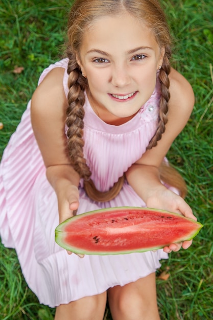 夏の屋外の昼間を楽しむスイカと幸せな女の子の肖像画