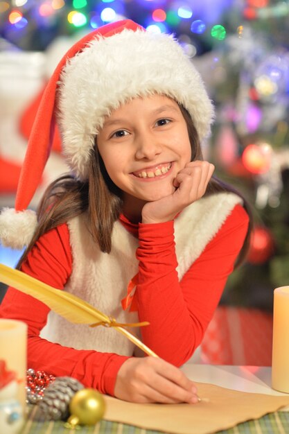 Portrait of happy girl writing letter to Santa Claus