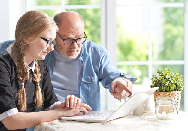 Portrait of happy grandfather and  granddaughter using laptop