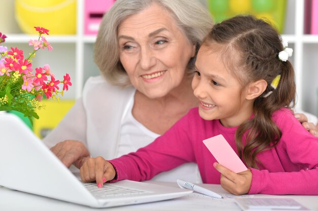 Portrait of happy grandmother and granddaughter shopping online