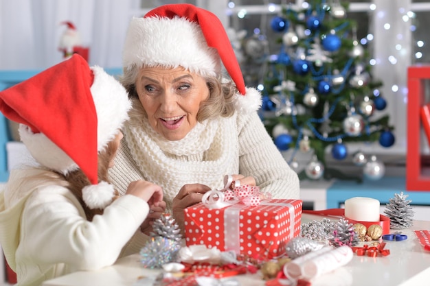 Portrait of happy grandmother and her little granddaughter preparing for Christmas together at home