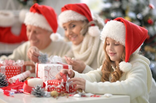 Portrait of happy grandparents and their cute granddaughter celebrating Christmas together at home