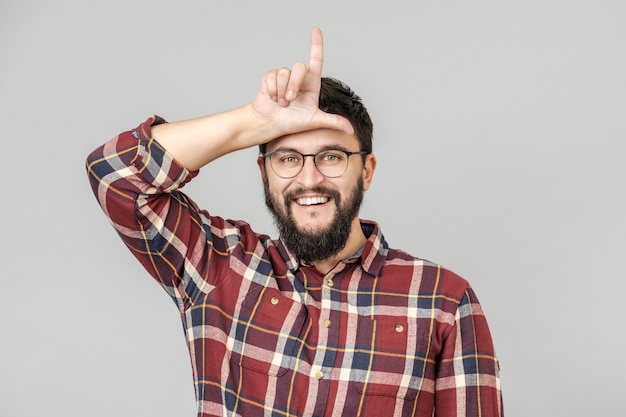 Portrait of happy guy with showing loser sign