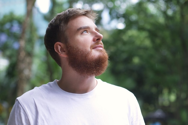 portrait happy handsome bearded young man in the park guy sit on a bench and enjoy warm fresh