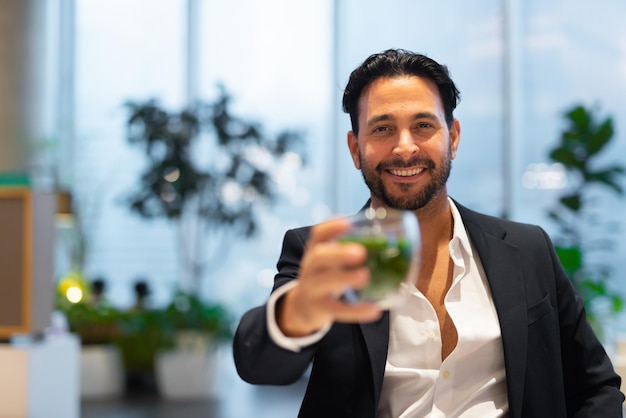 Ritratto di uomo d'affari ispanico bello felice alla caffetteria con tè verde