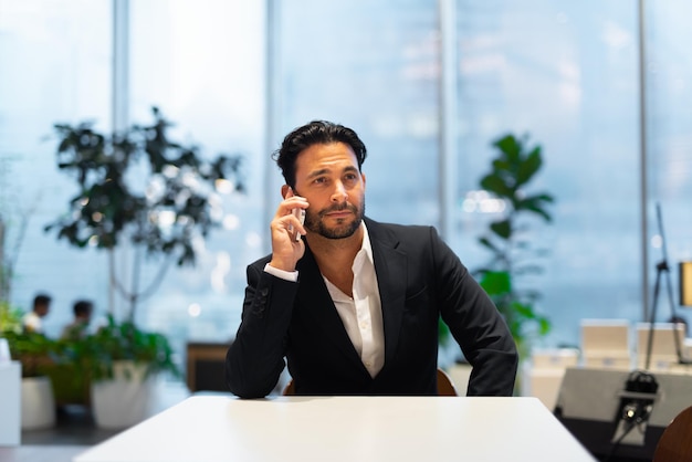 Portrait of happy handsome Hispanic businessman at coffee shop talking on phone